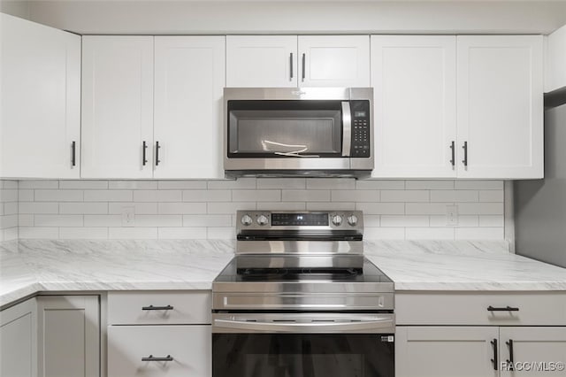 kitchen with decorative backsplash, stainless steel appliances, white cabinetry, and light stone countertops