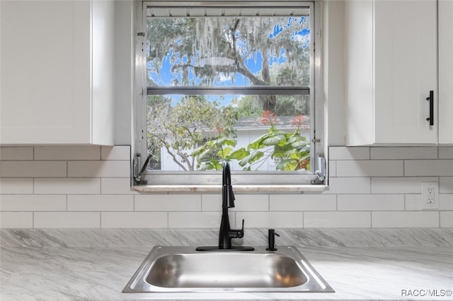 room details with decorative backsplash, sink, and white cabinets