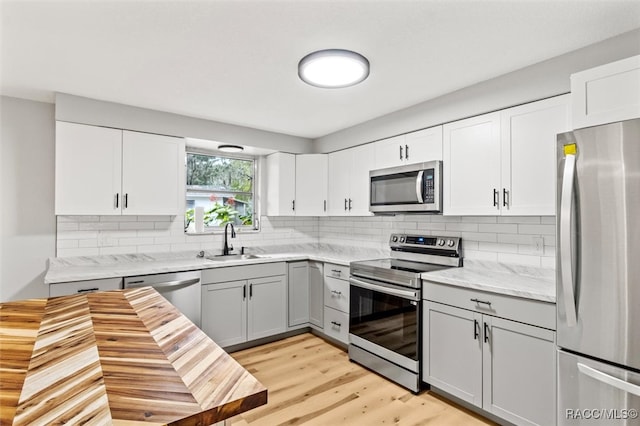 kitchen featuring appliances with stainless steel finishes, light wood-type flooring, white cabinetry, and sink