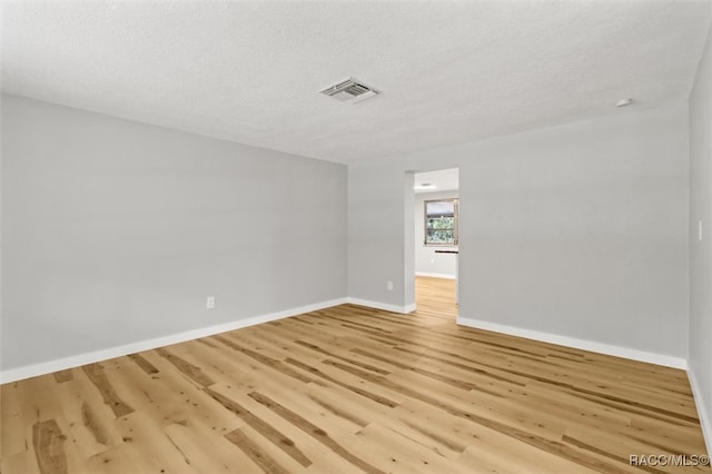 empty room featuring a textured ceiling and light wood-type flooring