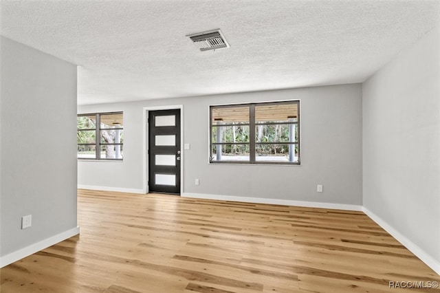 entrance foyer with a textured ceiling and light hardwood / wood-style floors