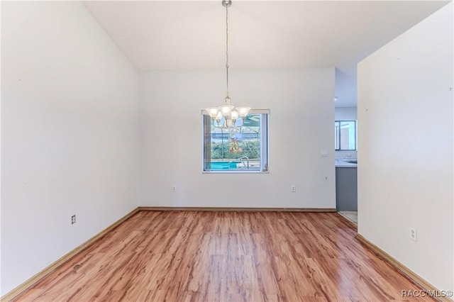 unfurnished dining area with an inviting chandelier and light wood-type flooring