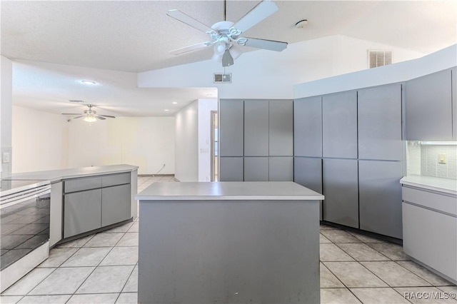 kitchen featuring gray cabinets, a kitchen island, stove, and light tile patterned floors