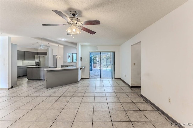 unfurnished living room featuring light tile patterned floors, a textured ceiling, and ceiling fan