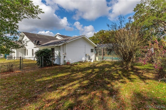 view of side of property with a yard and glass enclosure