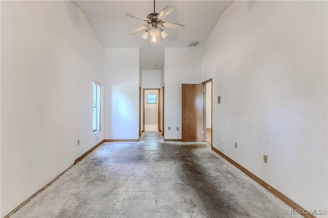 spare room featuring concrete flooring, a high ceiling, and ceiling fan