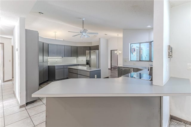 kitchen featuring tasteful backsplash, light tile patterned floors, appliances with stainless steel finishes, gray cabinets, and kitchen peninsula