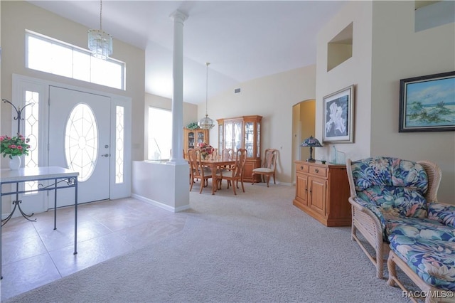 carpeted foyer featuring a towering ceiling and an inviting chandelier