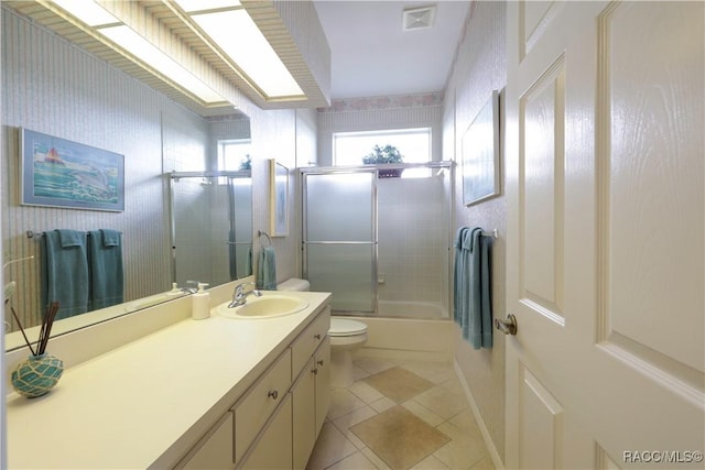 full bathroom featuring combined bath / shower with glass door, vanity, tile patterned flooring, and toilet