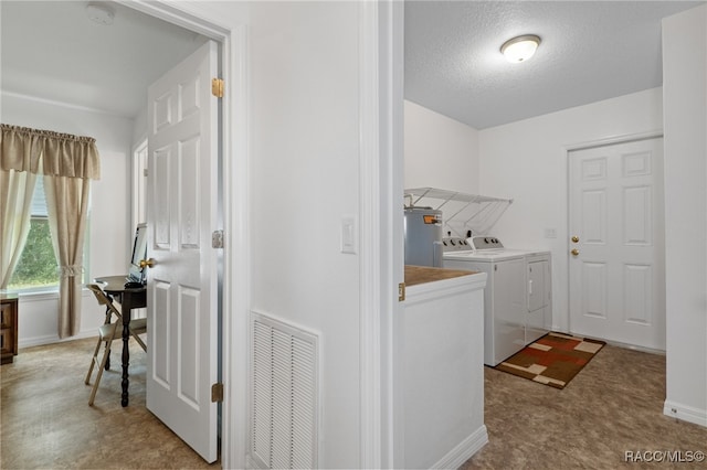 laundry area featuring washing machine and clothes dryer, electric water heater, and a textured ceiling