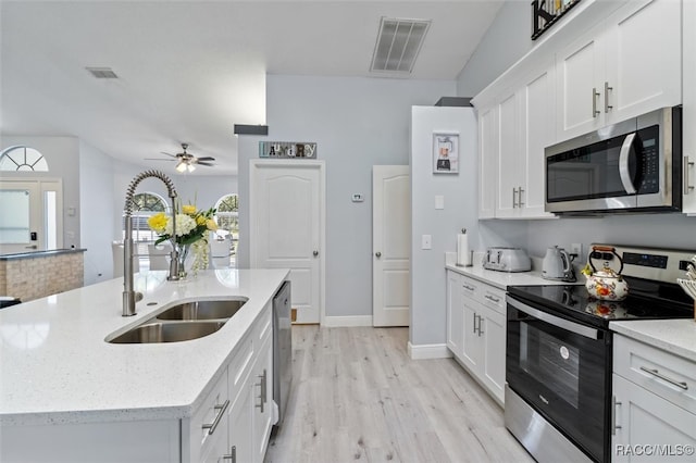 kitchen with a center island with sink, sink, appliances with stainless steel finishes, light hardwood / wood-style floors, and white cabinetry