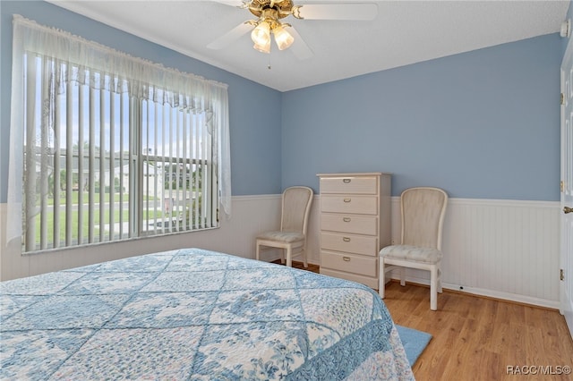 bedroom with multiple windows, a textured ceiling, light hardwood / wood-style flooring, and ceiling fan