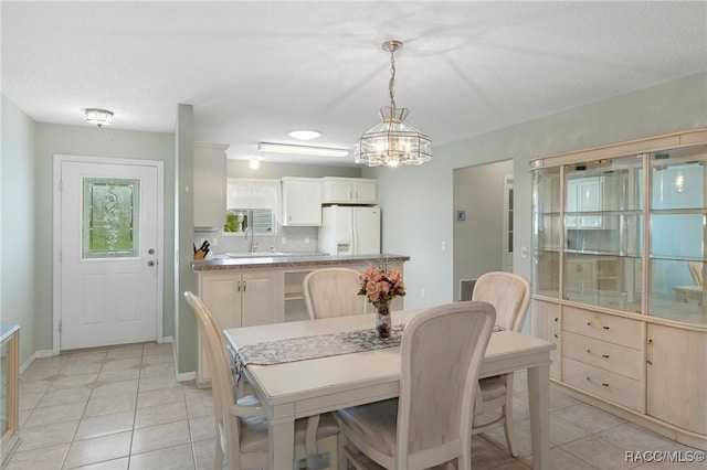 dining room featuring a notable chandelier, sink, light tile patterned floors, and a textured ceiling