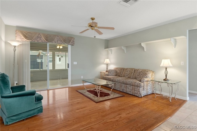 living room with a textured ceiling, light hardwood / wood-style floors, and ceiling fan