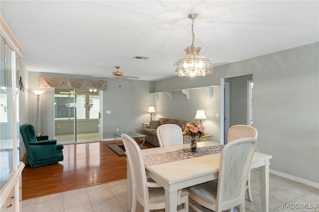 dining space with a textured ceiling, ceiling fan with notable chandelier, and light hardwood / wood-style floors