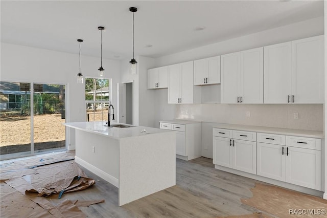 kitchen with a center island with sink, pendant lighting, and white cabinets