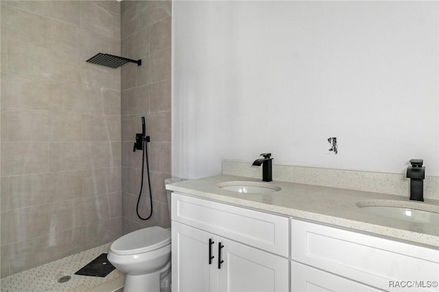 bathroom featuring toilet, tiled shower, and vanity