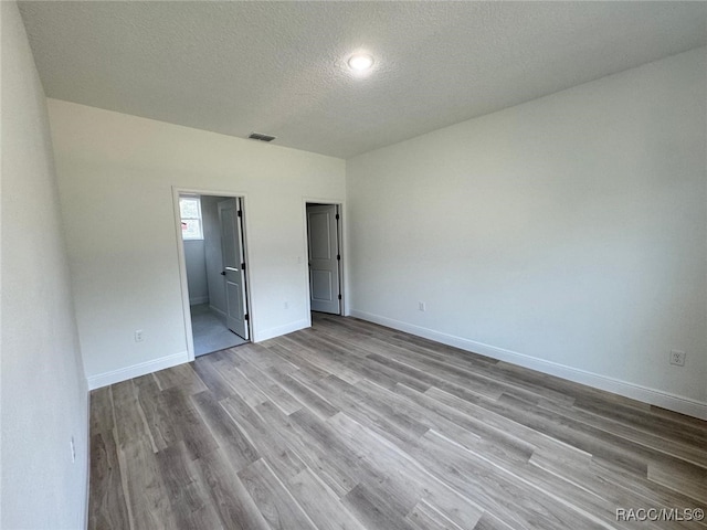 unfurnished bedroom featuring light wood-type flooring, a textured ceiling, and ensuite bathroom