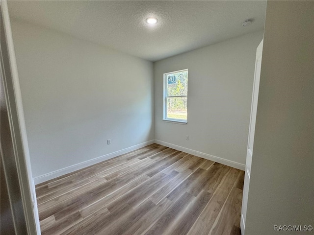 unfurnished room with a textured ceiling and light hardwood / wood-style flooring