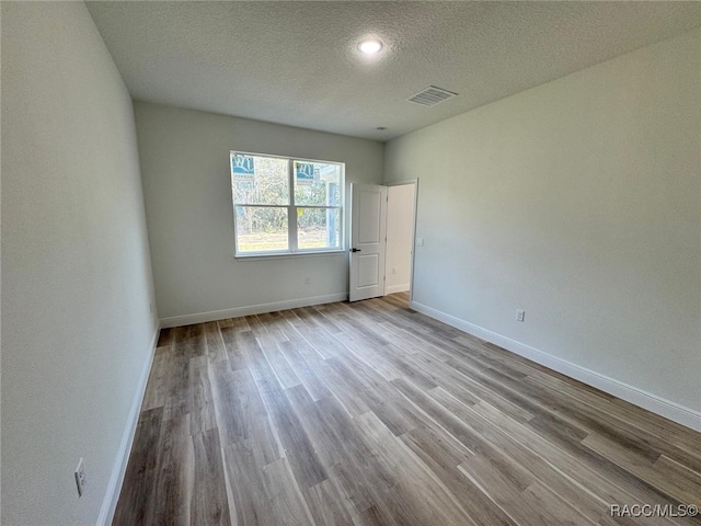 unfurnished bedroom featuring a textured ceiling and light hardwood / wood-style floors