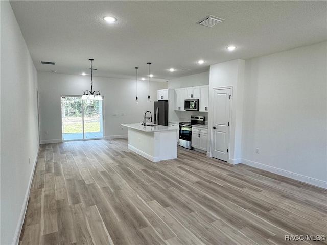 kitchen featuring stainless steel appliances, a kitchen island with sink, sink, decorative light fixtures, and white cabinetry