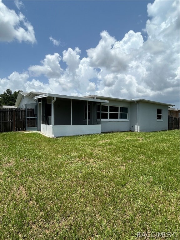 back of house with a sunroom and a yard