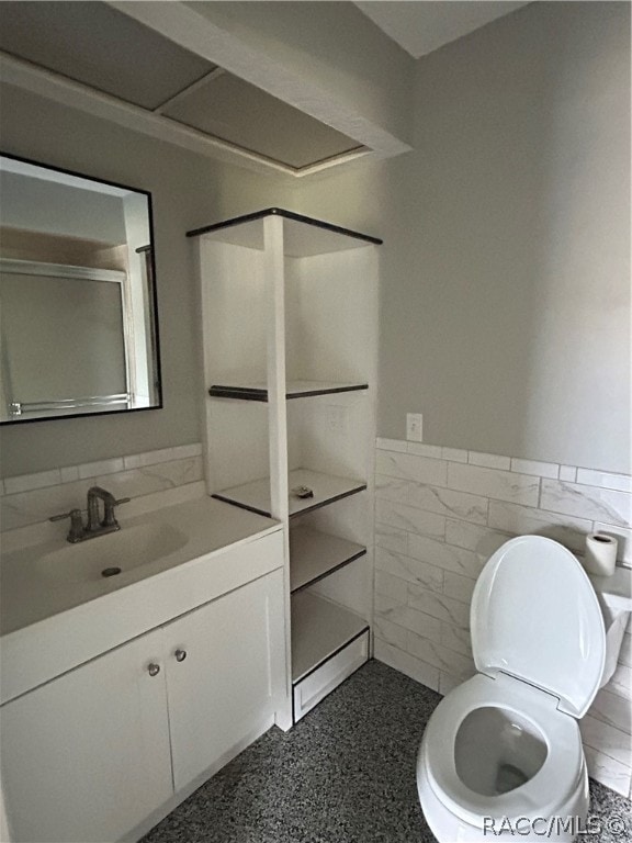 bathroom with vanity, toilet, tile walls, and walk in shower