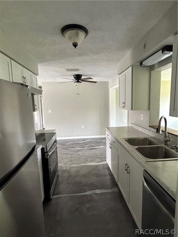 kitchen with a textured ceiling, stainless steel appliances, ceiling fan, sink, and white cabinets