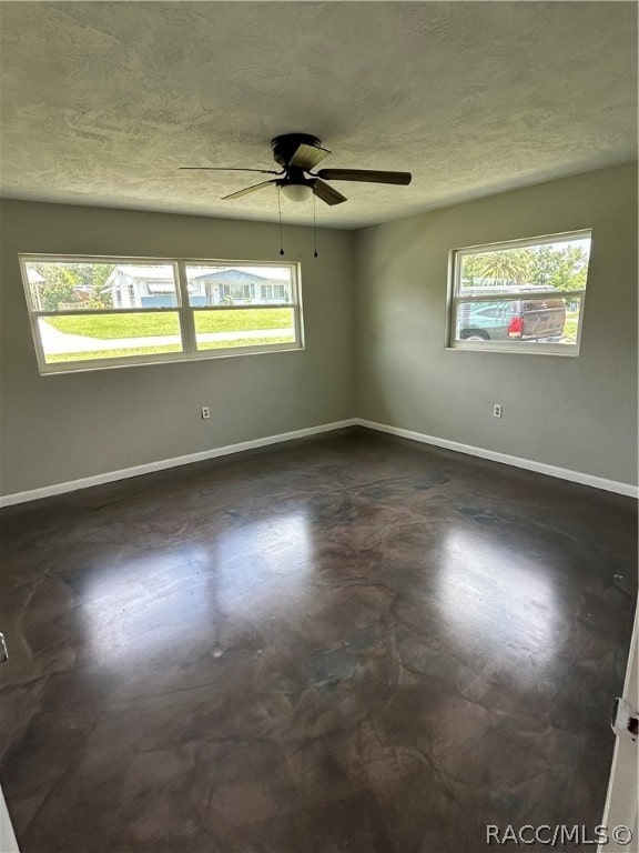 spare room with ceiling fan, a healthy amount of sunlight, and a textured ceiling