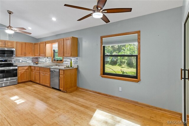 kitchen featuring lofted ceiling, sink, light hardwood / wood-style flooring, appliances with stainless steel finishes, and backsplash