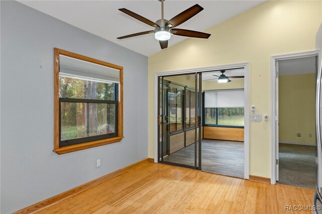 empty room with vaulted ceiling, plenty of natural light, and hardwood / wood-style floors