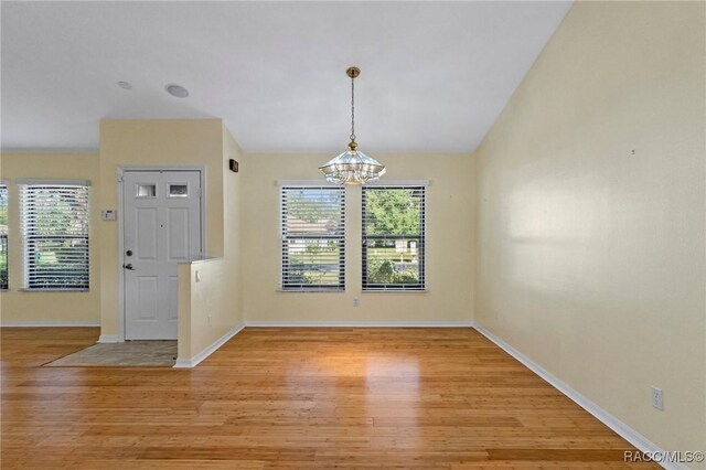 unfurnished dining area featuring a healthy amount of sunlight, a chandelier, and light wood-type flooring