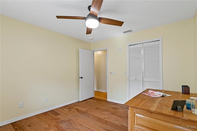 unfurnished office with ceiling fan and light wood-type flooring