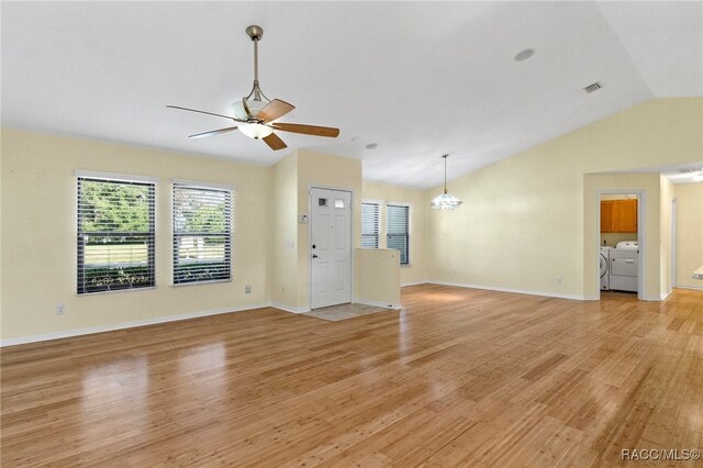 unfurnished living room featuring lofted ceiling, ceiling fan with notable chandelier, light hardwood / wood-style flooring, and washing machine and dryer