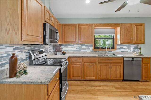 kitchen with sink, light stone counters, tasteful backsplash, light hardwood / wood-style flooring, and stainless steel appliances