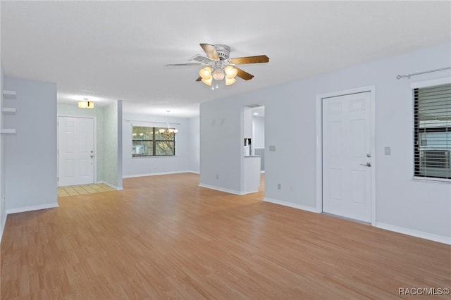 unfurnished living room featuring ceiling fan with notable chandelier and light hardwood / wood-style flooring