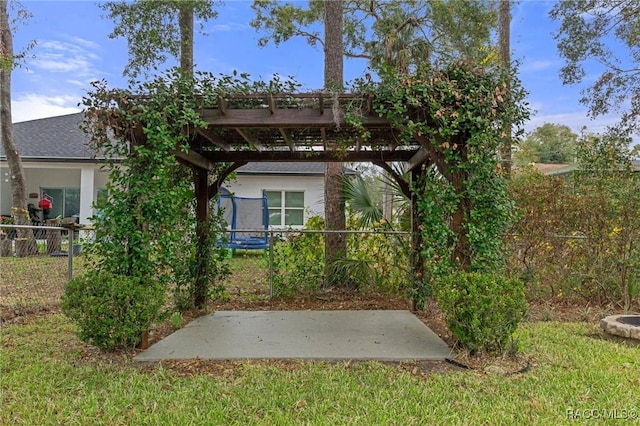 rear view of property featuring a trampoline, a patio area, a pergola, and a yard