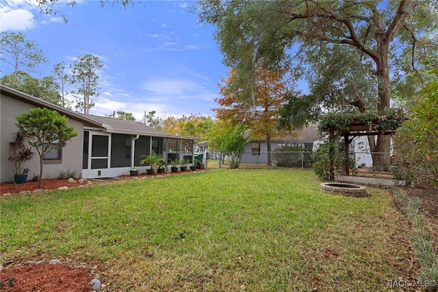 view of yard featuring a sunroom and an outdoor fire pit