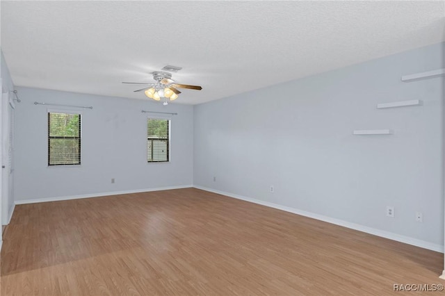 spare room with ceiling fan, a textured ceiling, and light wood-type flooring