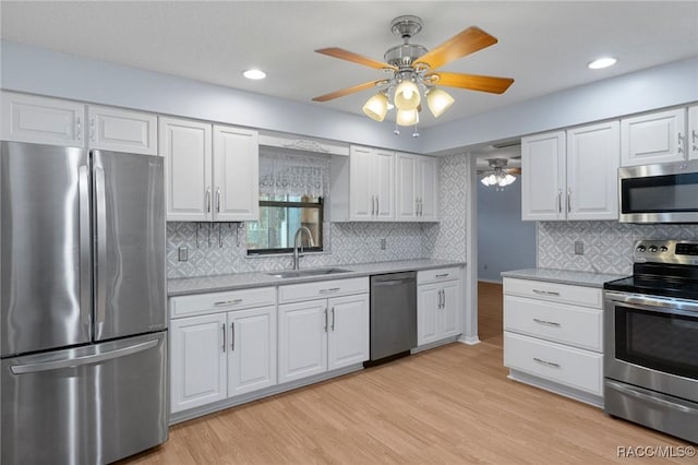 kitchen featuring sink, ceiling fan, appliances with stainless steel finishes, white cabinets, and light wood-type flooring