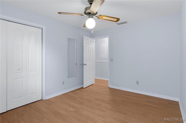 unfurnished bedroom with ceiling fan, a closet, and light wood-type flooring