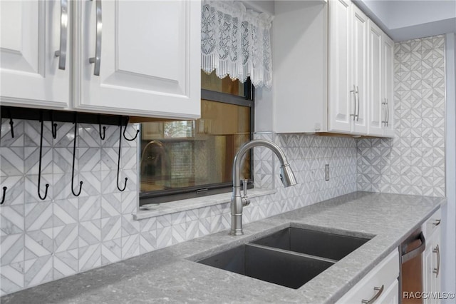 kitchen with backsplash, light stone counters, sink, dishwasher, and white cabinets