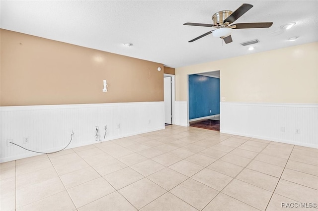 tiled empty room featuring ceiling fan and a textured ceiling