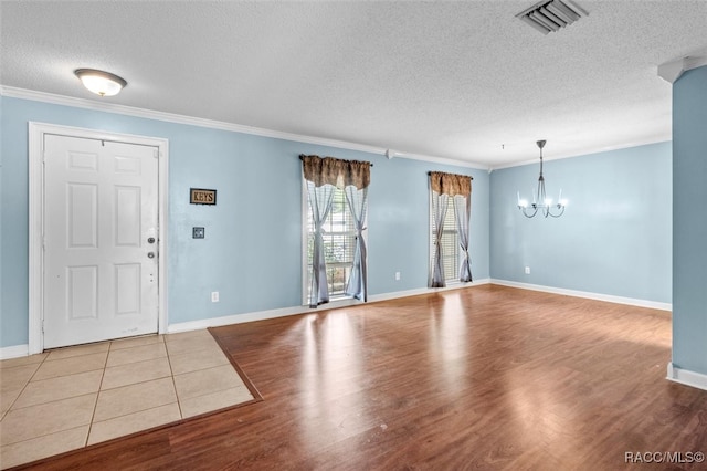 entrance foyer with light hardwood / wood-style flooring, a chandelier, a textured ceiling, and ornamental molding