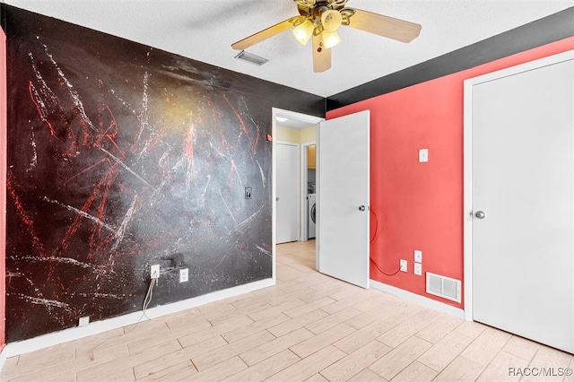 spare room with ceiling fan, light wood-type flooring, a textured ceiling, and washer / dryer