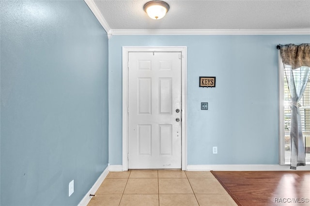 foyer featuring a textured ceiling, ornamental molding, and light tile patterned flooring