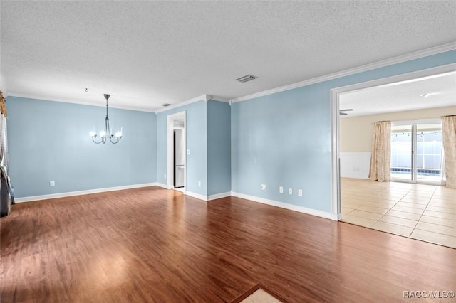 unfurnished room featuring a chandelier, a textured ceiling, light hardwood / wood-style floors, and ornamental molding