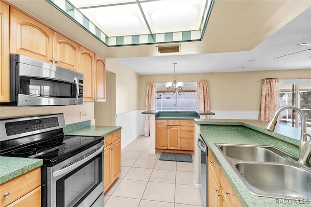 kitchen with a textured ceiling, stainless steel appliances, sink, pendant lighting, and light tile patterned floors