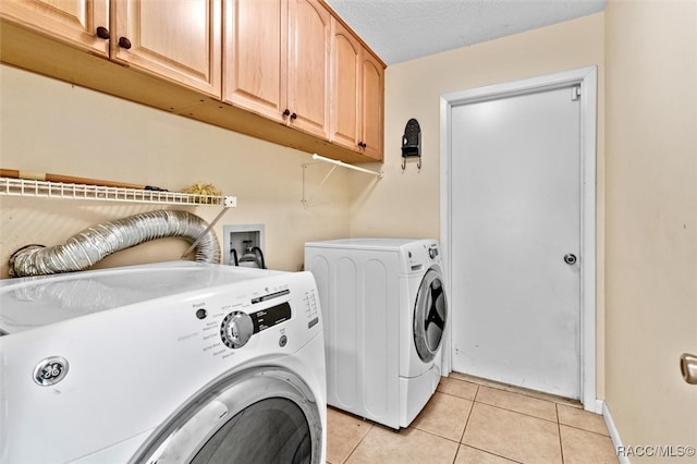 laundry area featuring cabinets, separate washer and dryer, a textured ceiling, and light tile patterned floors