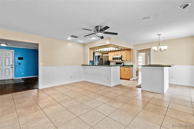 kitchen featuring ceiling fan with notable chandelier, a textured ceiling, stainless steel appliances, pendant lighting, and light tile patterned floors